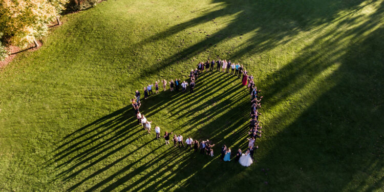Wedding guests lined up in the shape of heart with bride and groom marriage people