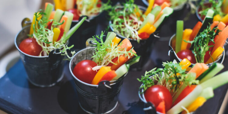 Beautifully decorated catering banquet table with variety of vegetables and different vegan vegetarian snacks on corporate christmas birthday party event or wedding celebration